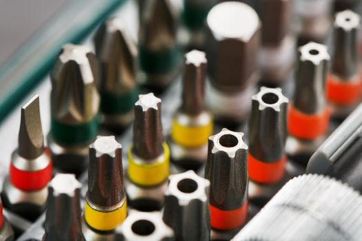 A set of metal power bits in a box on a gray background, for repair and maintenance