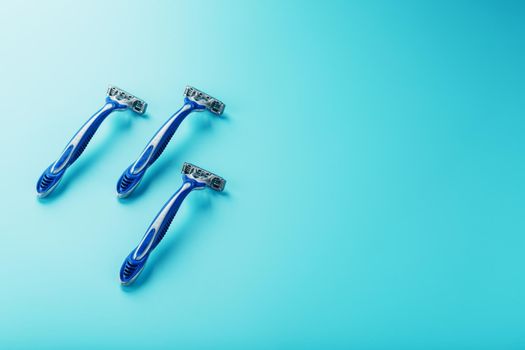 Three shaving machines on a blue background with free space, top view