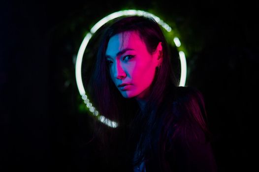 Portrait of an Asian man against the background of a circular lamp in the studio with neon light