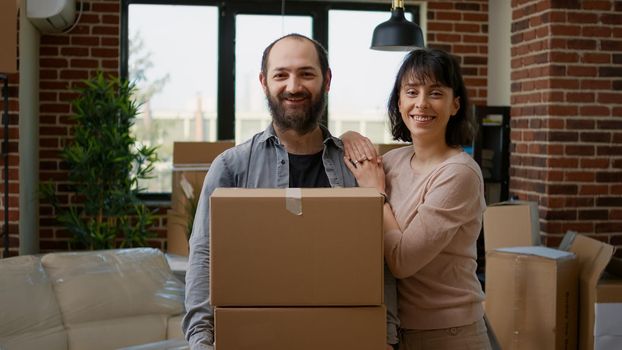 Portrait of relationship people with cardboard boxes to move in together in new house property. Married couple unpacking furniture and apartment things, moving in new rented flat on loan.