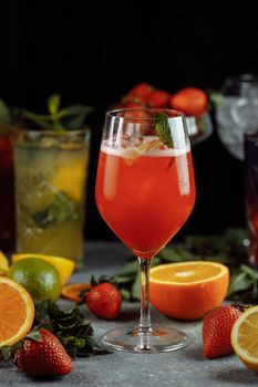 Colorful refreshing drinks for summer, cold strawberry lemonade juice with ice cubes in the glasses garnished with sliced fresh lemons.