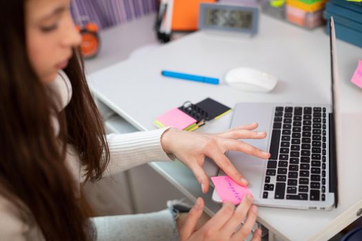 A modern method of learning English. A young brunette girl sticks a card that says computer on her laptop.