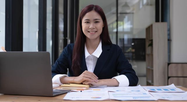 Charming Asian woman working at the office using a laptop Looking at the camera..