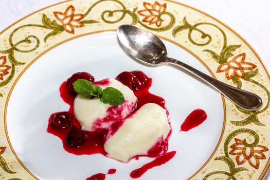 Panakota with cherry jelly and mint leaves on a white background.