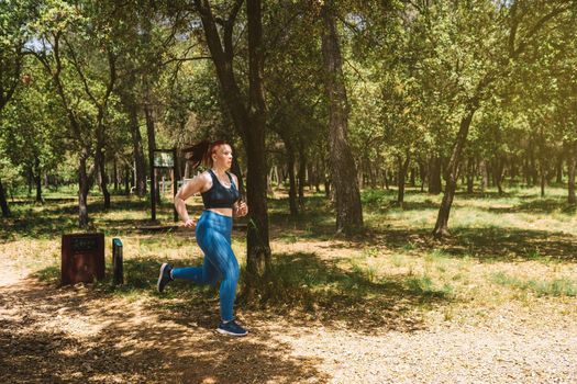 young female athlete training, running in nature to tone the body. athlete practising outdoor sport. health and wellness lifestyle. outdoor public park, natural sunlight.