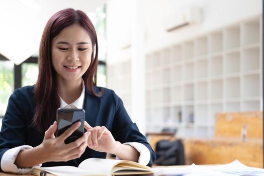 Asian woman talking on the phone and working on a laptop with a smiling face, Business Cell Phone Conversations, Working at cafe, cafe lifestyle, Stay cafe, New normal, learning, Social distancing..