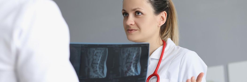 Portrait of female doctor deliberate with colleague about patients medical history. Worker hold scan result of clients checkup. Medicine, treatment concept