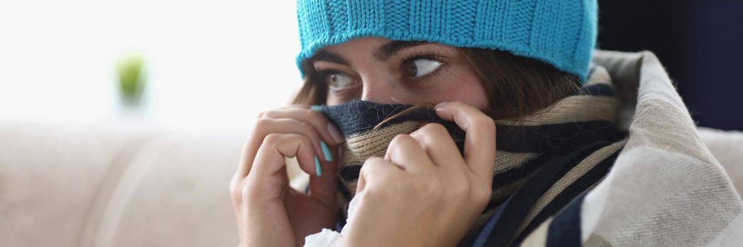 Portrait of young woman hide nose in scarf feeling cold because of high temperature. Girl get care at home, stay on self isolation. Covid, health concept