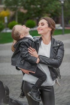 Mom carries her daughter in her arms while walking in the city