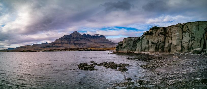 Green rock, fjord and mountain peaks panorama in Iceland