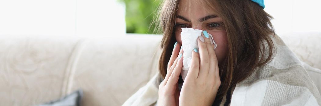 Portrait of woman wipe wet running nose with tissue dressed in warm clothes because of cold. Stay on self isolation, recover at home. Health, ill concept