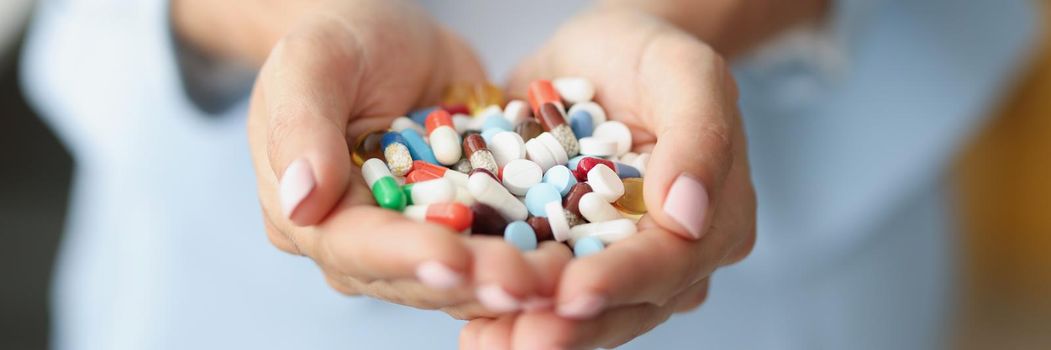 Close-up of woman holding bunch of colourful medications on palm for treatment. Pills and capsules in hand. Shopping at pharmacy, medicine, health concept