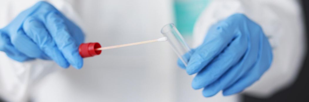 Close-up of doctor in protective suit medical mask gloves holding swab saliva sample for diagnostic covid. Nasopharyngeal test for patient. Virus concept