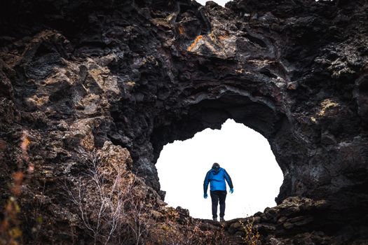 Unrecognizable tourist going through huge lava field hole