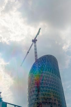 Detail of a new building skyscraper under costruction with crane and rainbow light.