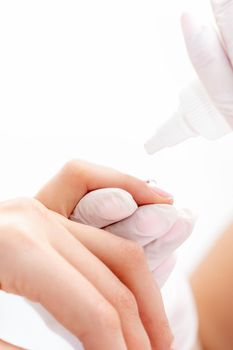 Professional manicurist pouring oil on nails manicure of woman in beauty salon.