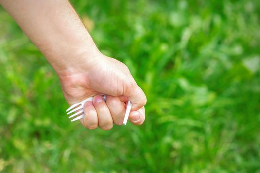 Hand of a little girl holding plastic trash on a background of green grass in the park