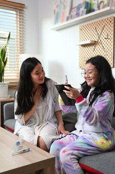 Happy teenage woman and her young sister playing as doctor together in living room.