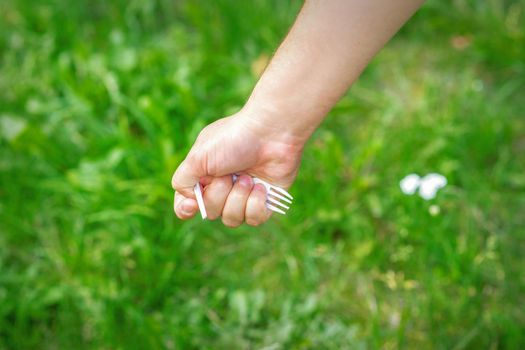 Hand of a little girl holding plastic trash on a background of green grass in the park