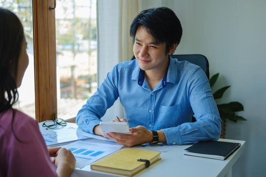 financial, Planning, Marketing and Accounting, portrait of Asian male Economist using calculator to calculate investment documents with partners on profit taking to compete with other companies.