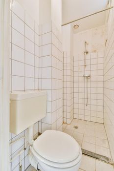 Glass partition between shower tap and wall hung toilet in modern restroom at home