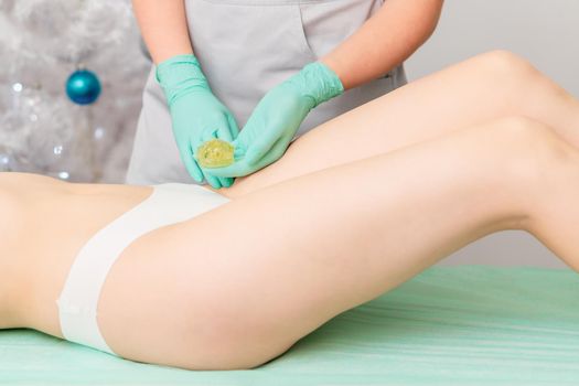 Beautician waxing legs of woman in spa center. Soft focus