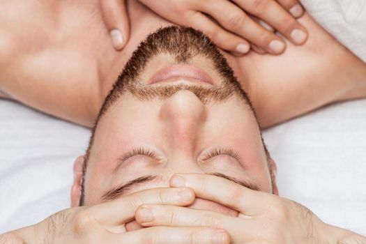 Top view of man receiving relaxing head massage by hands of massage therapist