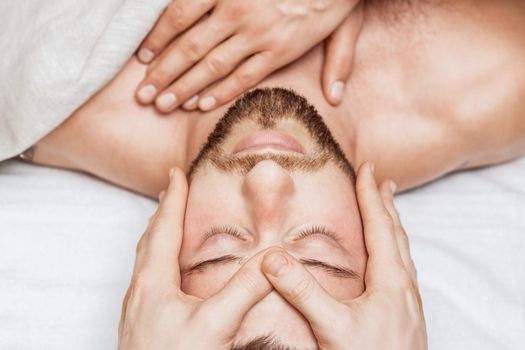 Man receiving relaxing head massage by massage therapist hands, top view.