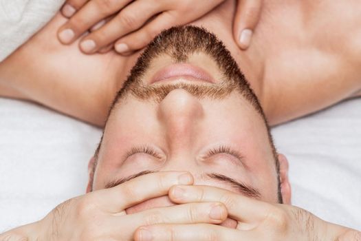 Top view of hand massage of young man by hands of two masseurs