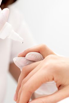 Professional manicurist pouring oil on nails manicure of woman in beauty salon.