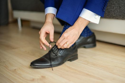 Groom is wearing shoes in blue wedding clothes indoors. The businessman wears shoes