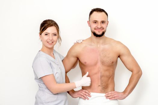 Young caucasian man with bare chested before and after waxing his hair with thumb up of hand of beautician standing on white background