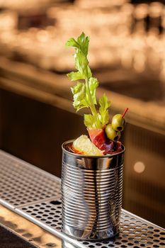 The cocktail bloody mary . Making cocktail with ingredients on wooden background . Free space for text. Still life. Original cocktail in a tin can