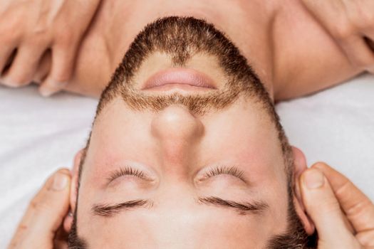 Relaxing man enjoying head and shoulder massage top view.