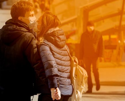 Man wearing facial hygiene mask outdoors. Virus protection, ecology, air pollution, environmental awareness concept. The guy and the girl are masked.
