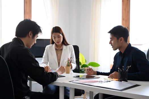 Group of creative people brainstorming, discussing startup business plan in modern office.