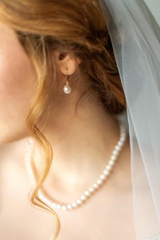 Wedding pearl earring on ear of beautiful caucasian young bride. Selective focus