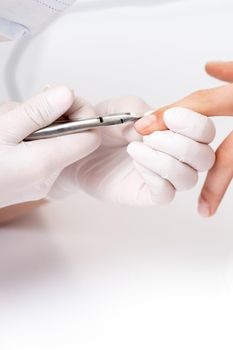 Close up of manicurist using manicure cutter to remove cuticle of female nails in manicure salon
