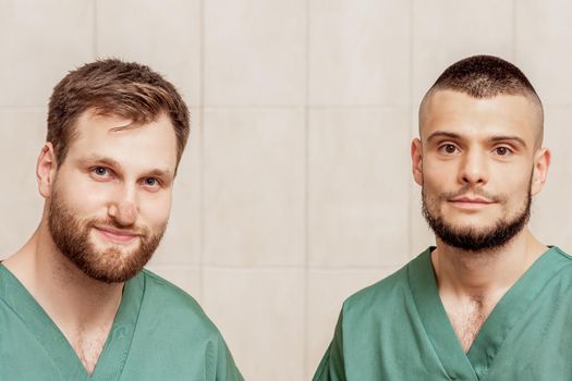 Portrait of two male massage therapists or doctors wearing working clothes at work place.