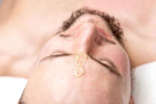 Close up of liquid wax between the eyebrows of a young man before waxing in beauty salon