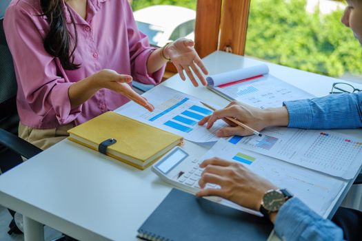 Negotiation, Analysis, Discussion, Portrait of an Asian young economist and marketer pointing to a financial data sheet to plan investments to prevent risks and losses for the company