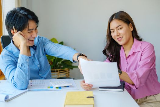 Negotiation, Analysis, Discussion, Portrait of an Asian young economist and marketer pointing to a financial data sheet to plan investments to prevent risks and losses for the company