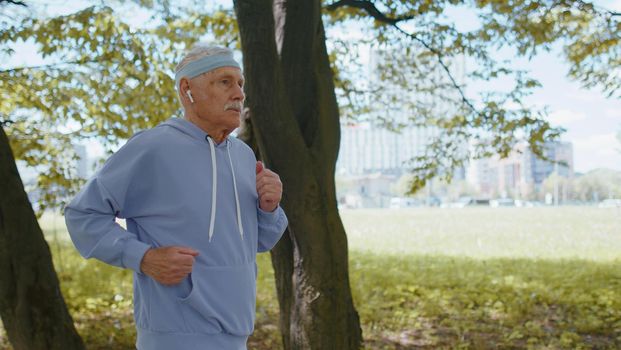 Athletic fitness senior elderly sport runner man training. Workout cardio outside in city park at morning. Happy old grandfather enjoying healthy lifestyle. Active retired mature people motivation