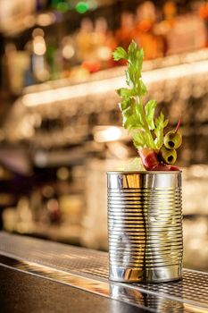 The cocktail bloody mary . Making cocktail with ingredients on wooden background . Free space for text. Still life. Original cocktail in a tin can