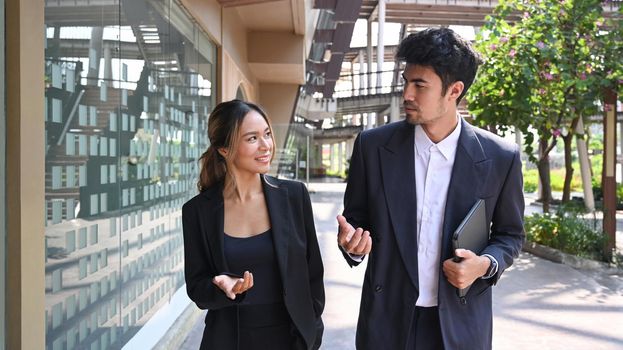 Shot of two businesspeople having a discussion while walking outside modern office building.