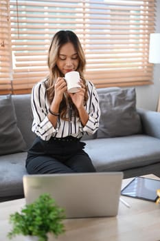 Beautiful young woman drinking coffee while spending leisure time at home.