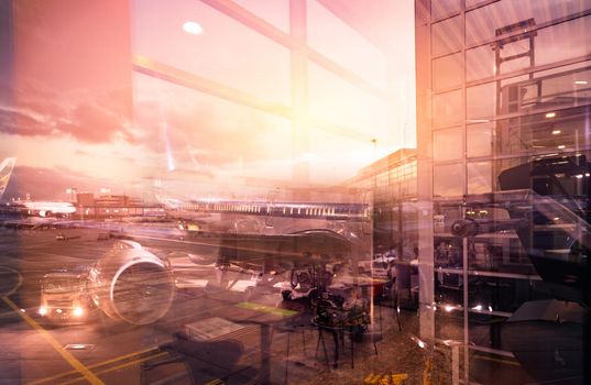 View from glass window of the airport building to outside. Passenger plane docking at the airport at night. Commercial airplane and service truck in the airport. Air transportation. Runway traffic.