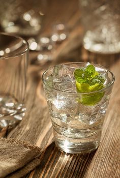 Glass of gin tonic with lime and ice over a wooden table. Close-up. Still life. Copy space