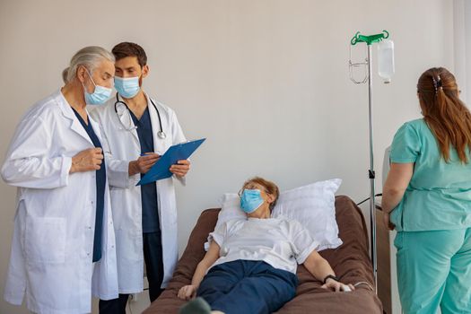 Professional doctors discuss over patient's diagnosis standing in hospital ward. High quality photo