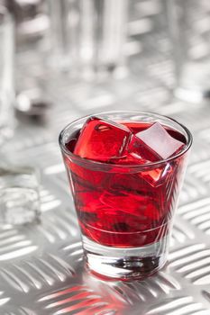 Red alcoholic cocktail with ice and cherry juice on iron table. Close-up. Still life. Copy space